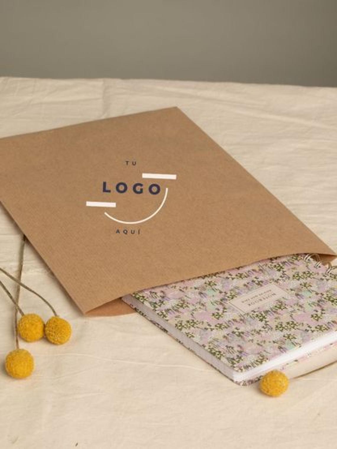 Sobre de papel kraft personalizable con logotipo, mostrando una libreta en su interior