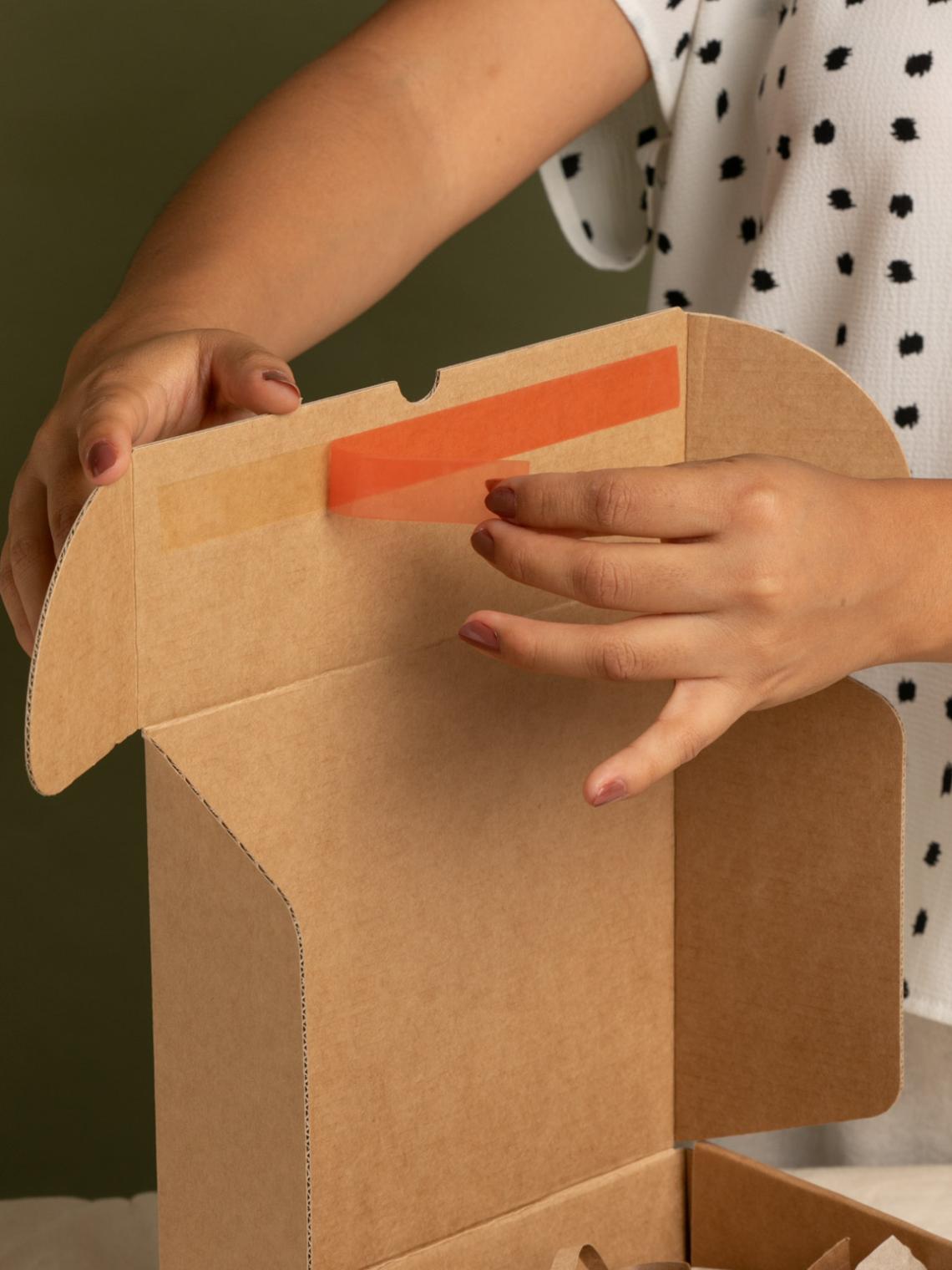 Una mano tirando de la tira que posee la caja ecommerce