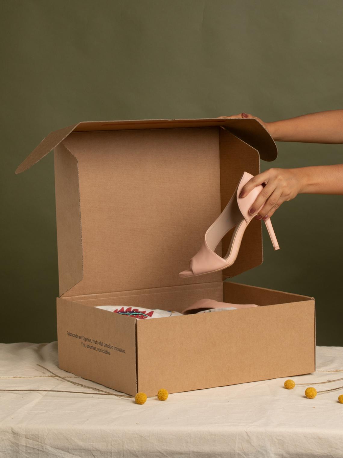 Caja de cartón ecommerce y una mano sujetando un tacón encima