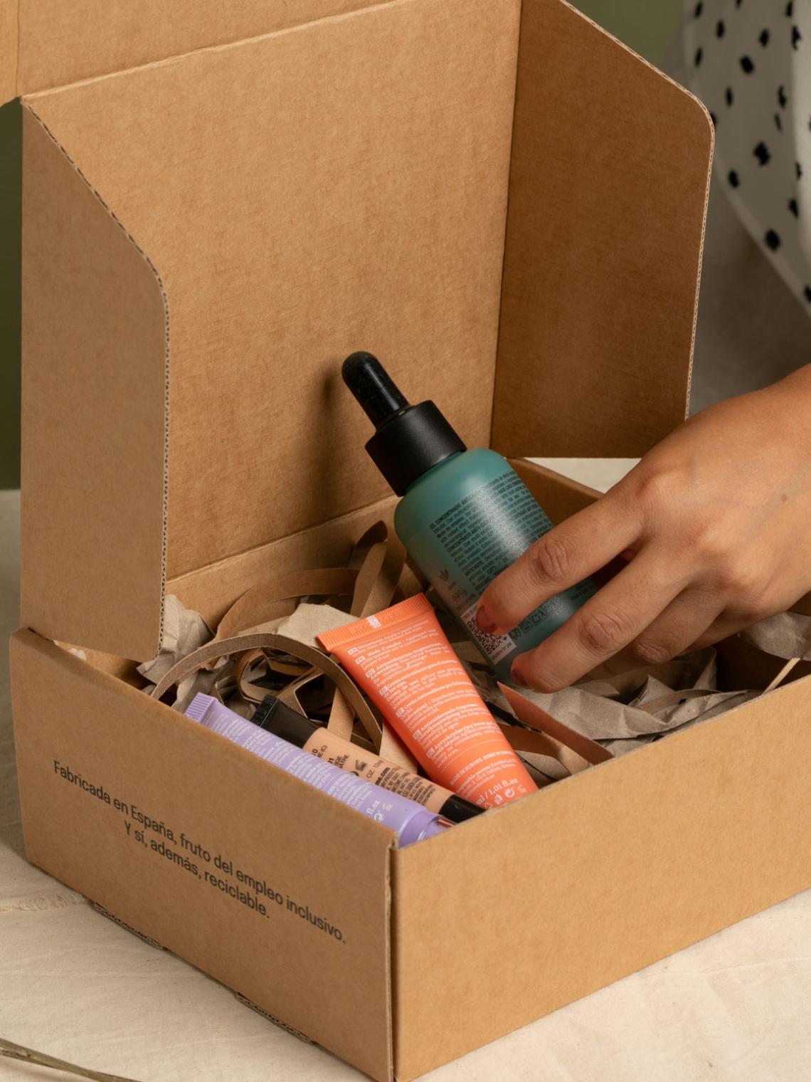 Una mano mostrando los productos que hay dentro de la caja, productos cosméticos
