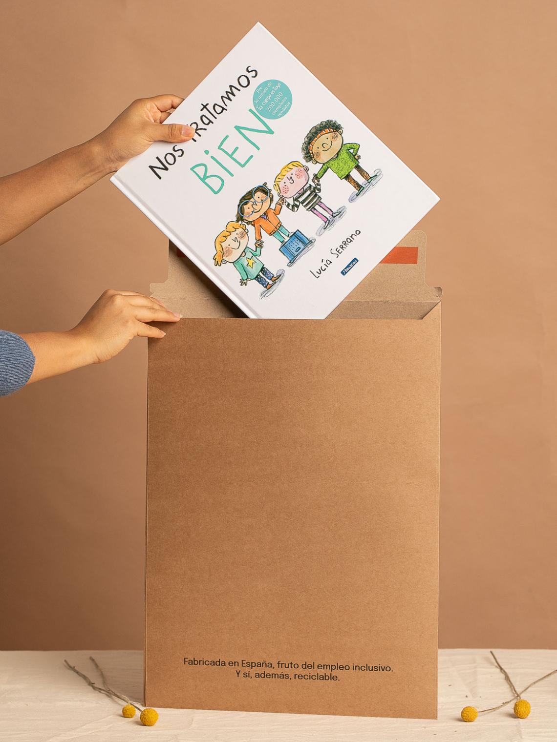 Manos introduciendo un libro en un sobre kraft grande fabricado en España por Bolsalea. Embalaje reciclable y elaborado mediante empleo inclusivo.