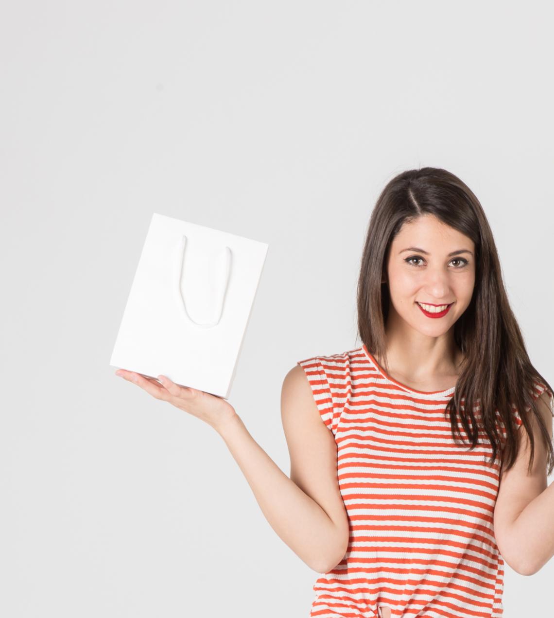Una mujer sujetando con una mano las bolsas de papel de lujo