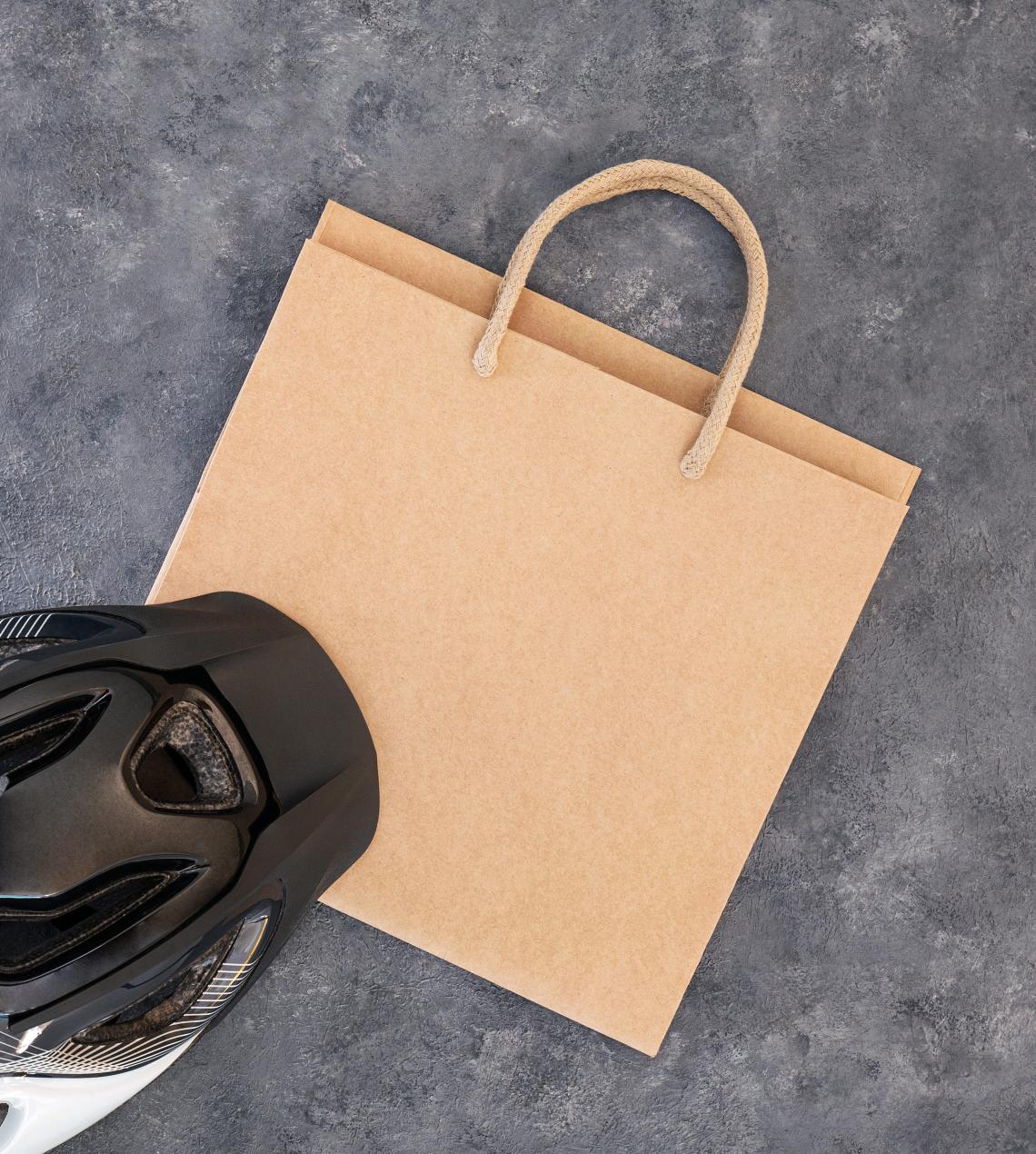 Bolsas de papel blancas con base ancha junto a un casco de bicicleta