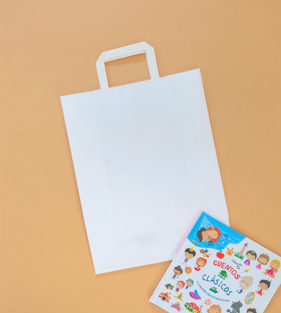 Bolsas de papel blanco medianas de asas planas junto a un libro