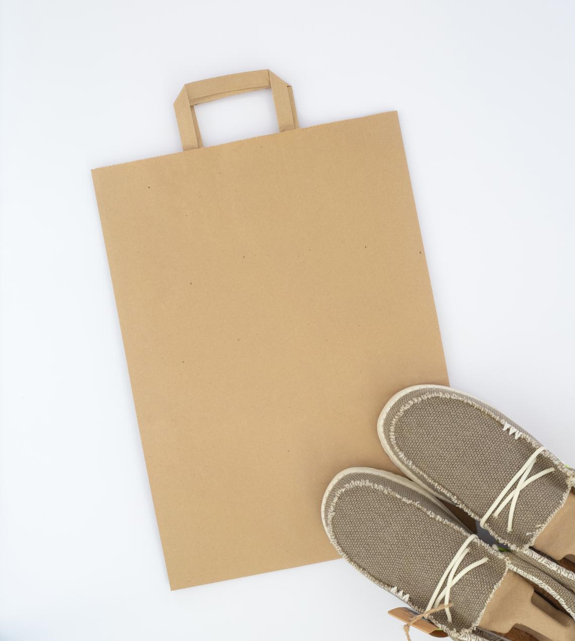 Bolsas de papel con asas planas junto a unos zapatos