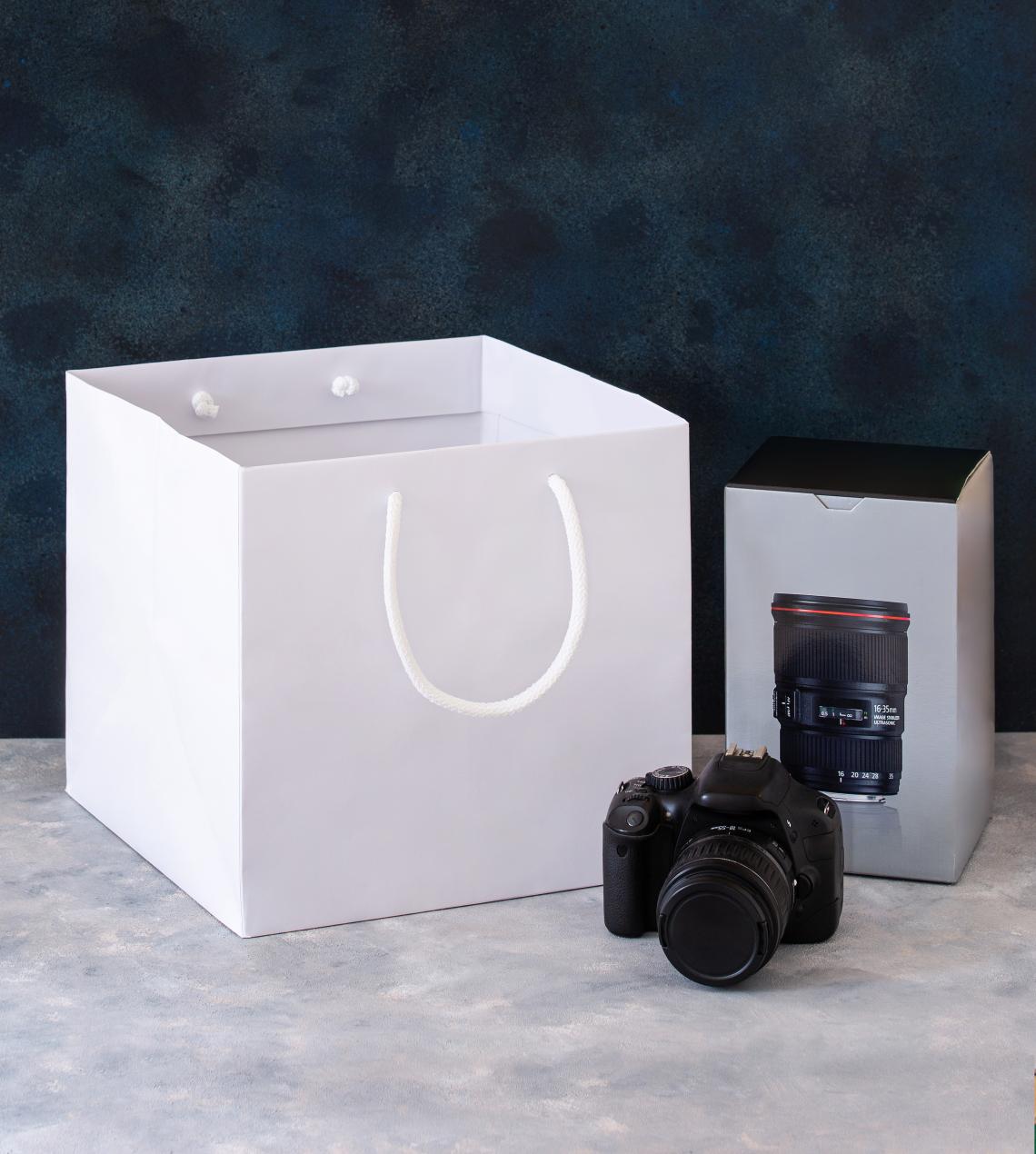 Bolsas de papel blancas con base ancha junto a una cámara