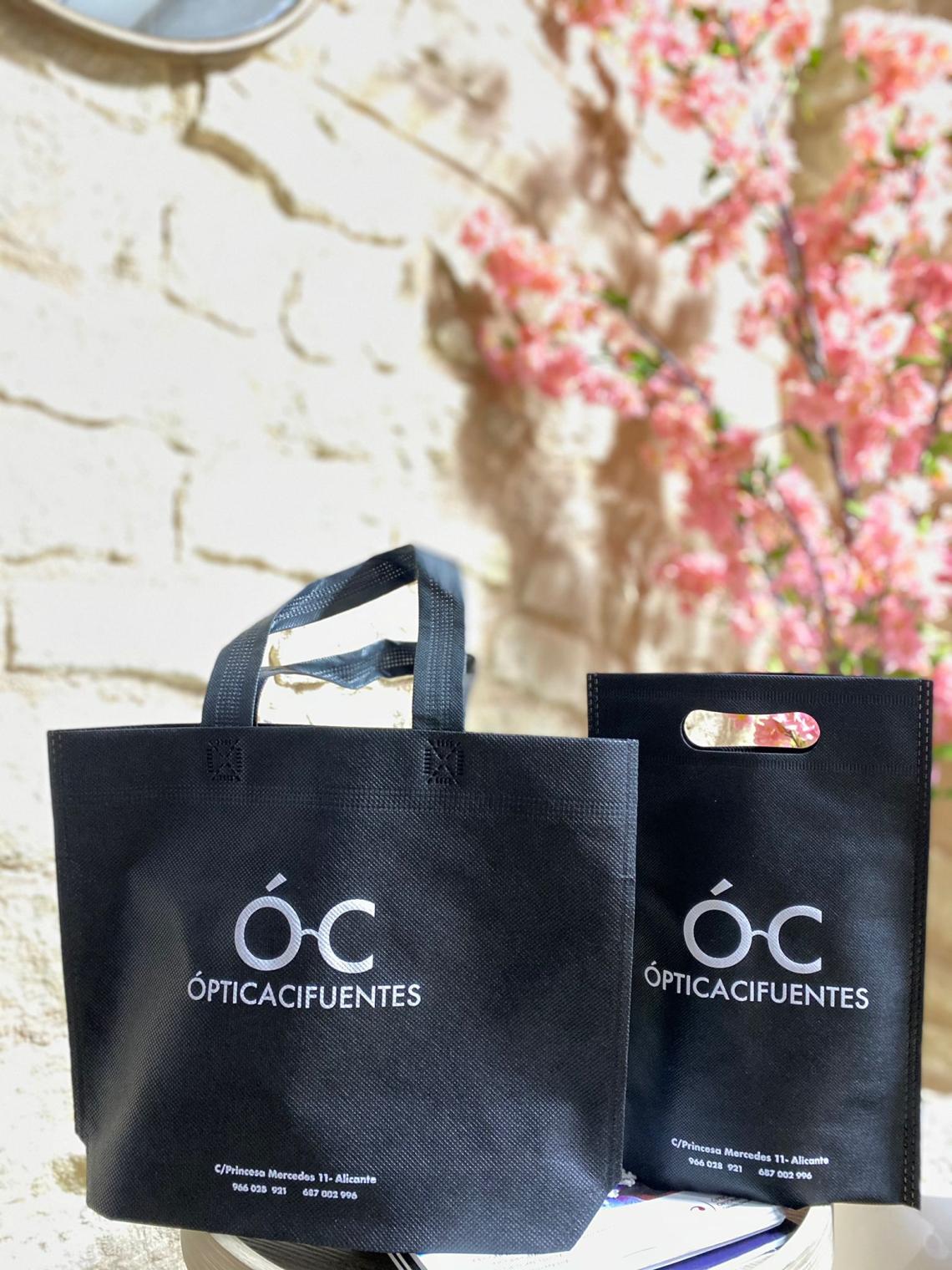 Bolsas negras con asas troqueladas junto a otra bolsa con asas cortas impresas