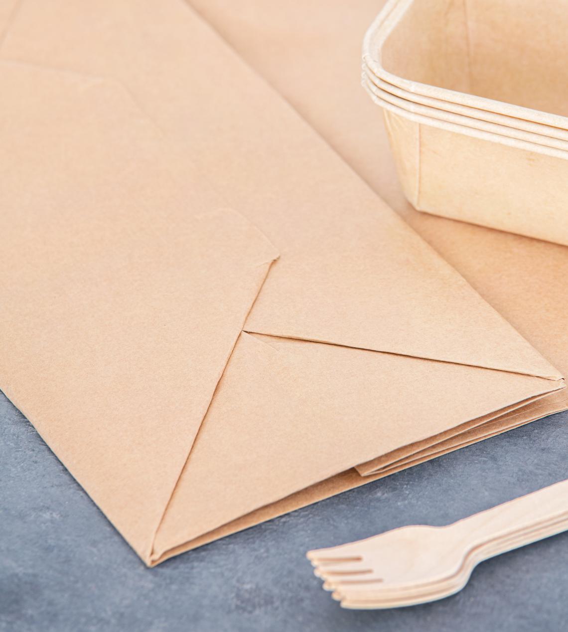 Bolsas grandes de papel reciclado take away junto a platos de comida