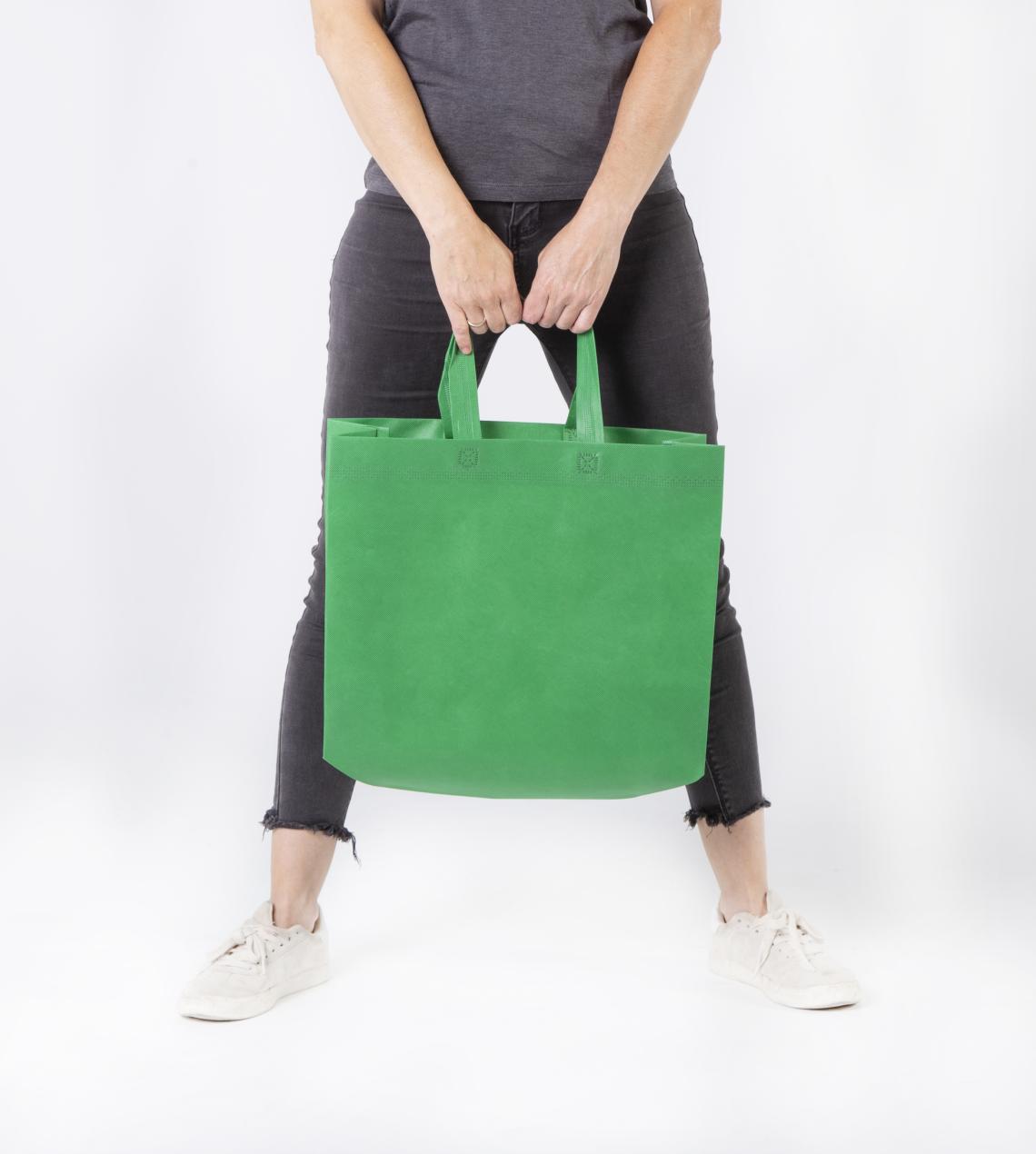 Bolsas verdes con fuelle lateral sujetadas por una mujer
