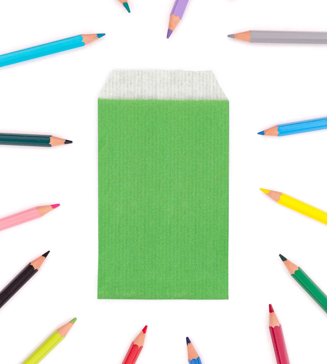 Sobres de papel pequeños verdes con lápices alrededor