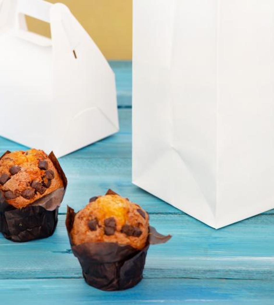 Bolsas blancas de papel con pasteles al lado