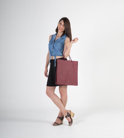Venta de bolsas de tela con asas de cordón hechas en España Bolsas de tela con asas de cordón de color burdeos sujetadas por una mujer