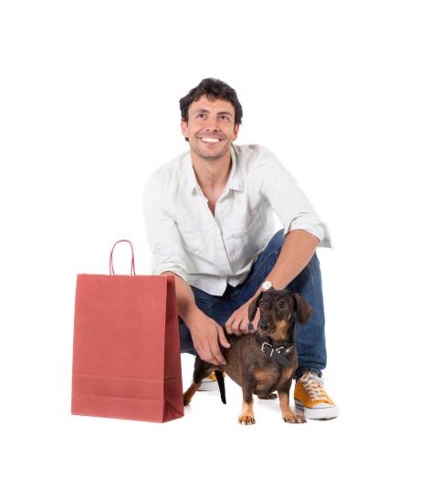 Bolsas de papel granate junto a un hombre y un perrito