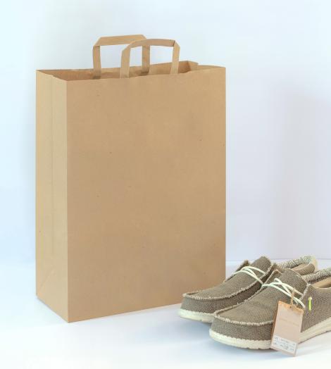 Bolsas de papel con asas planas junto a unos zapatos