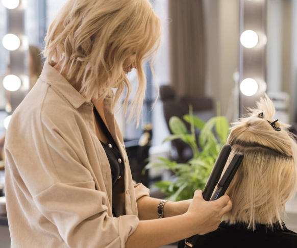 Una mujer planchando el pelo a otra mujer