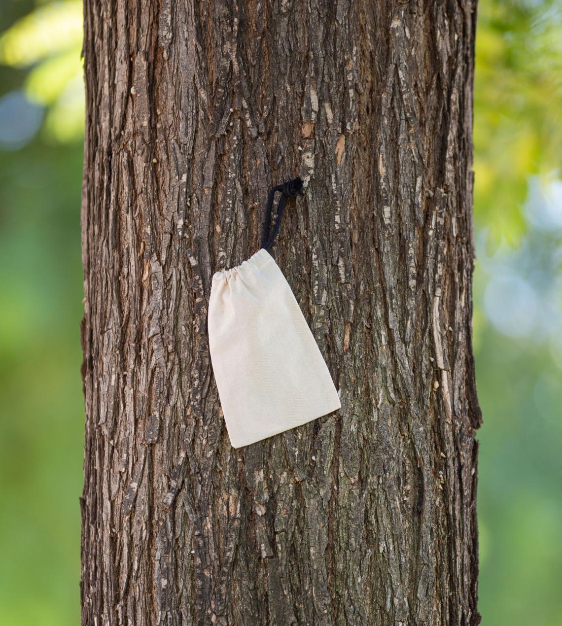 Sacos pequeños de algodón orgánico sobre tronco del árbol