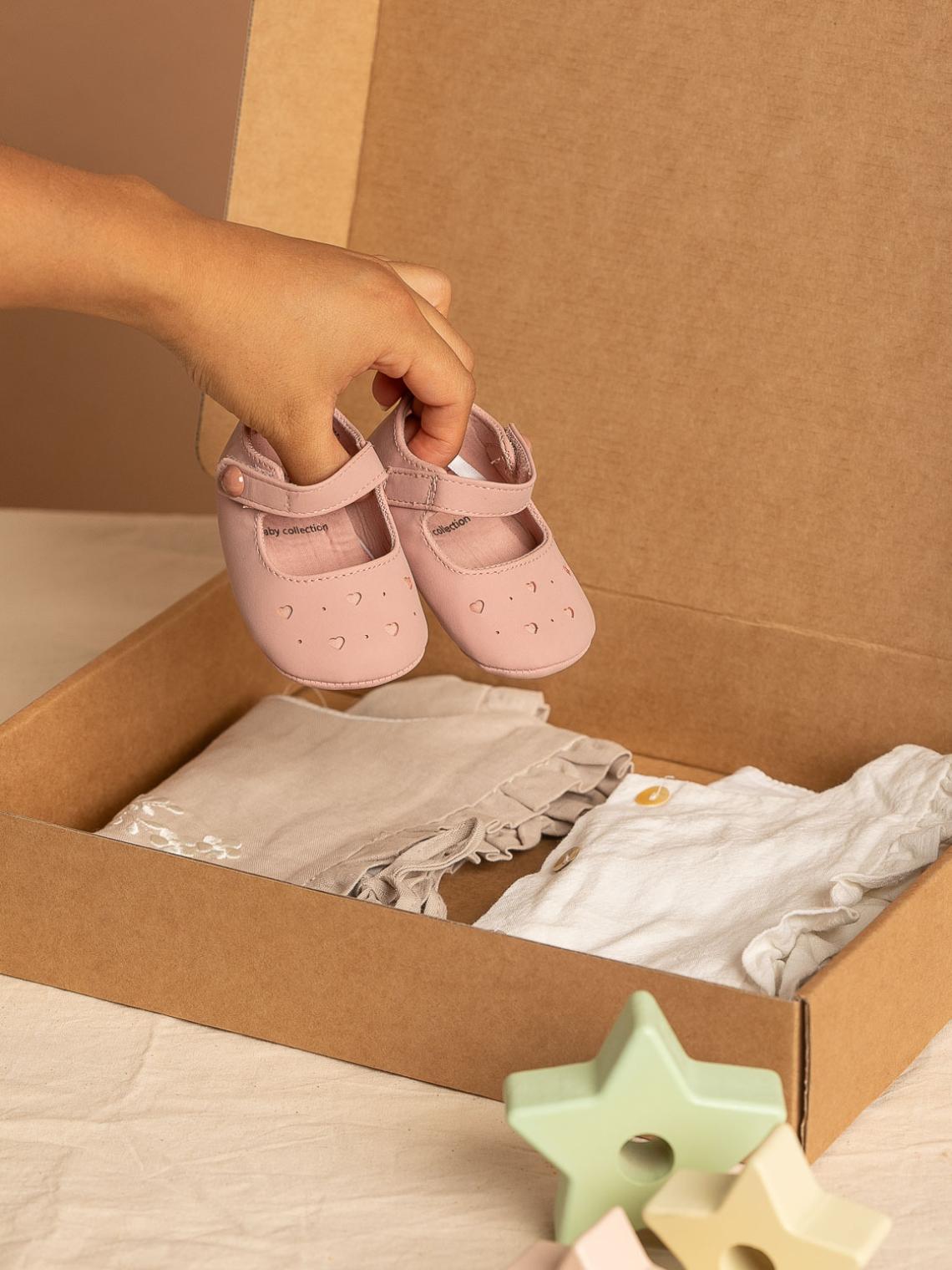 Caja ecommerce con ropa y una mano sujetando unos zapatos encima de la caja