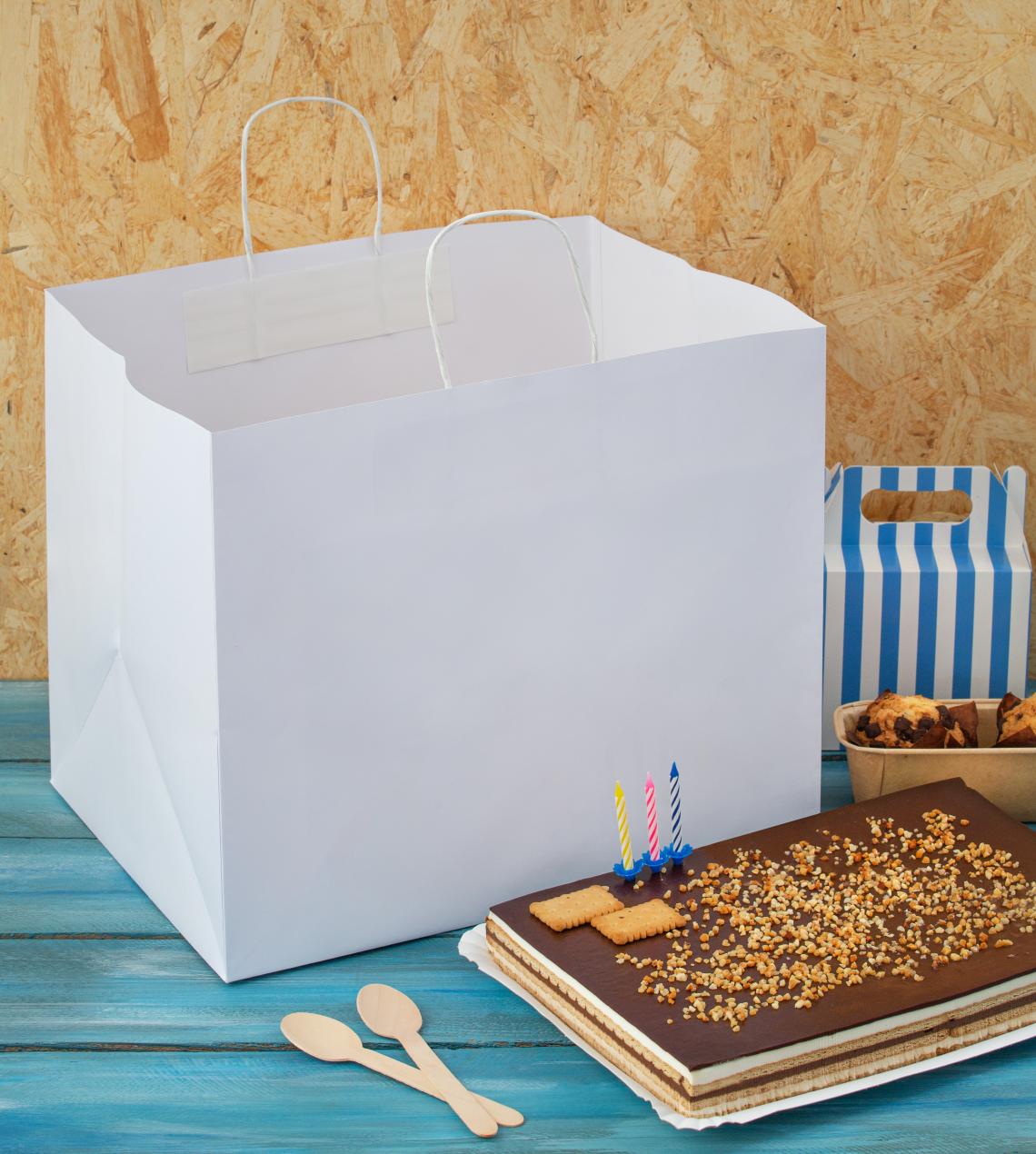 Bolsas de papel blancas de base ancha con una tarta al lado
