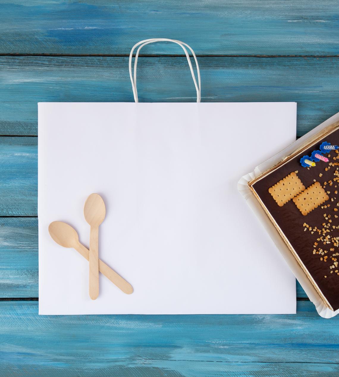 Bolsas de papel blancas de base ancha con una tarta al lado