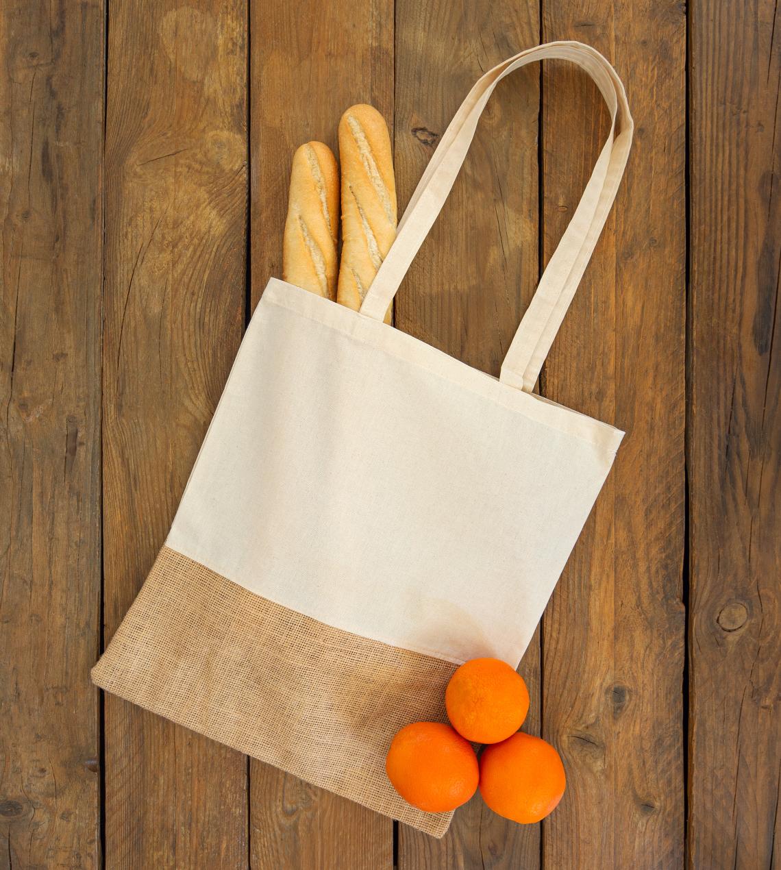 Bolsas de algodón orgánico y yute con  pan y naranjas al lado