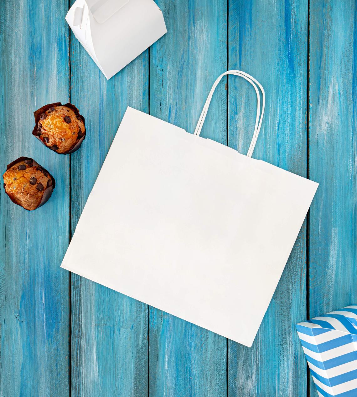 Bolsas blancas de papel con pasteles al lado