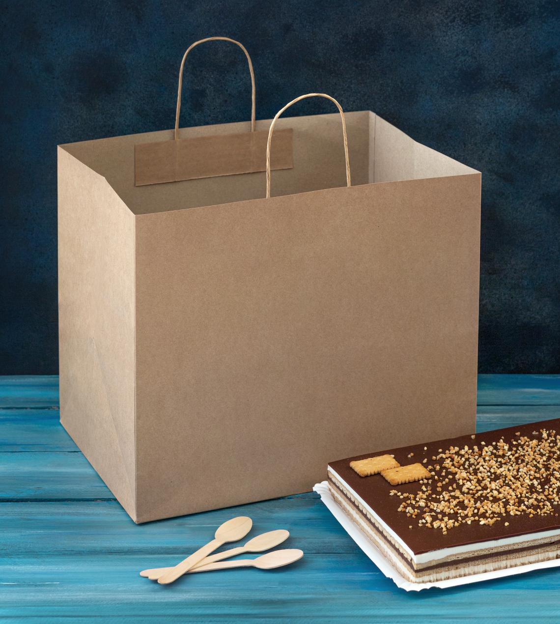 Bolsas de papel grandes con una tarta al lado