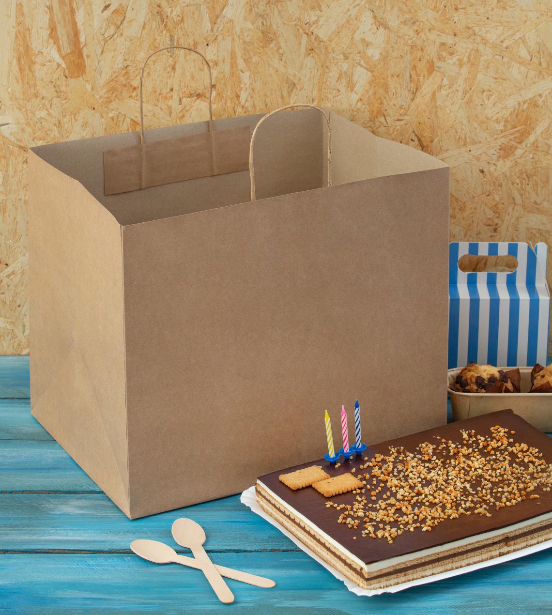 Bolsas de papel grandes con una tarta al lado