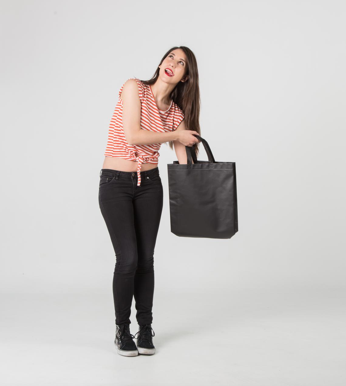 Bolsas negras con acabado laminado de tela reciclada sujetadas por una mujer