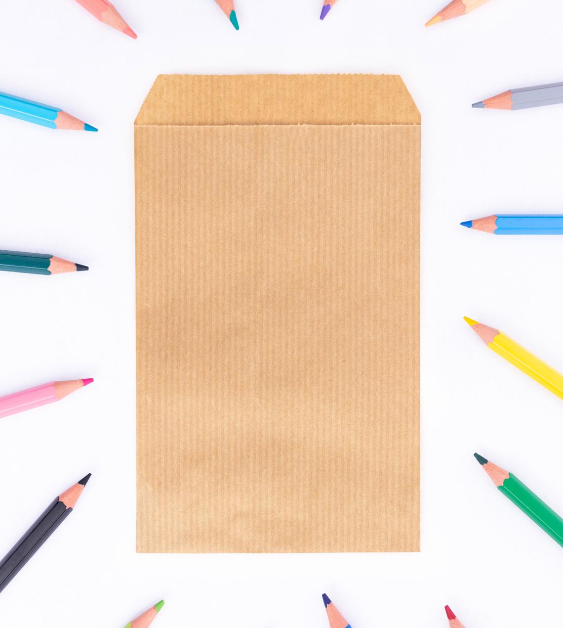 Sobres de papel kraft con lápices de colores alrededor
