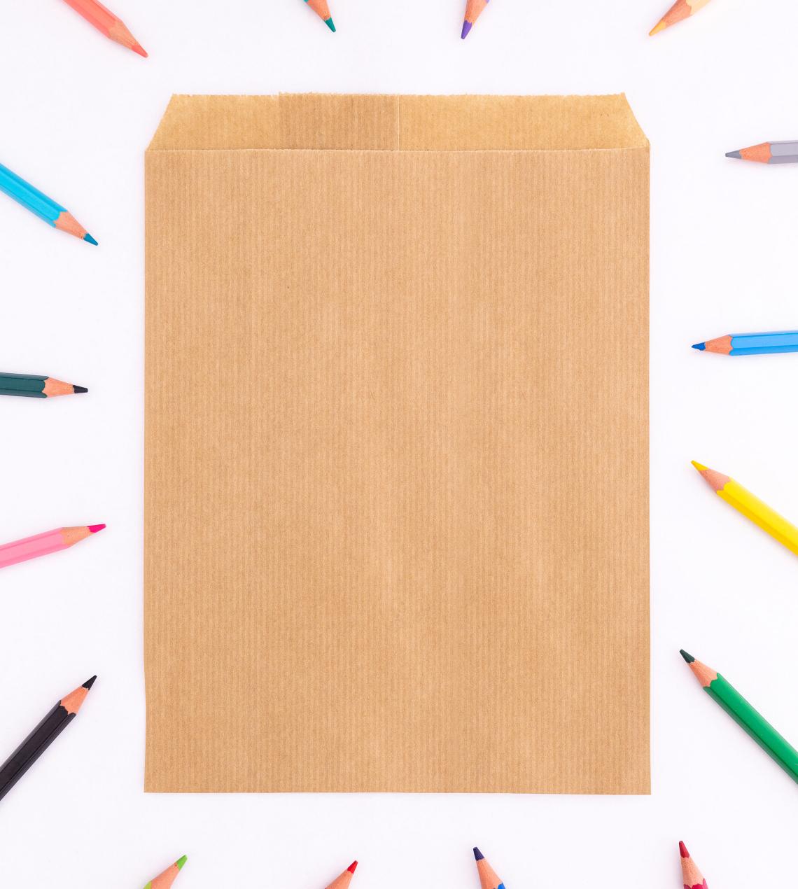 Sobres de papel kraft con lápices de colores alrededor