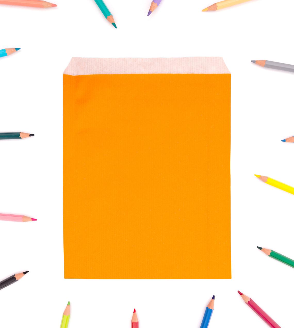 Sobres de color naranja de papel con lápices de colores alrededor