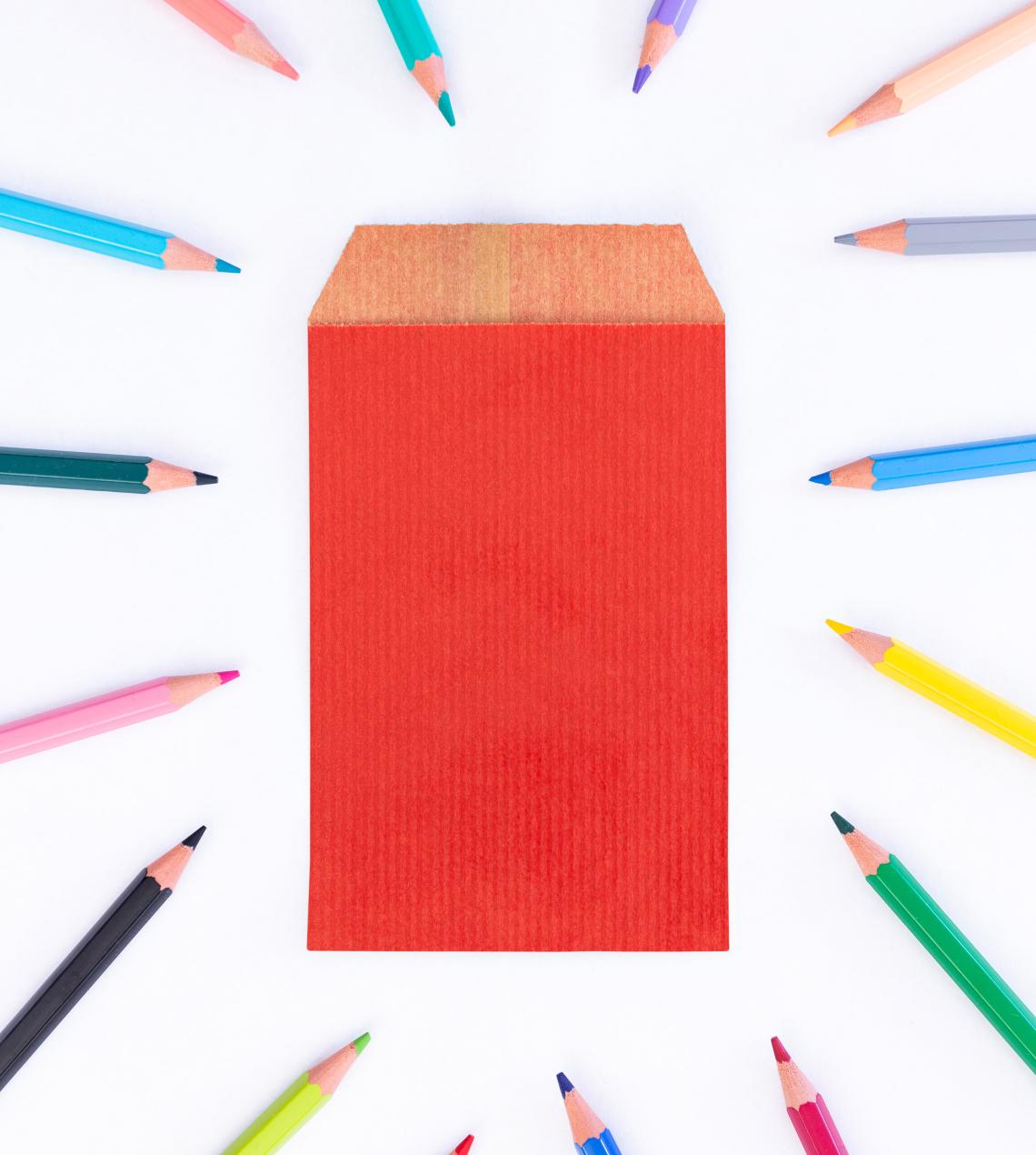 Sobres de papel pequeños con lápices alrededor