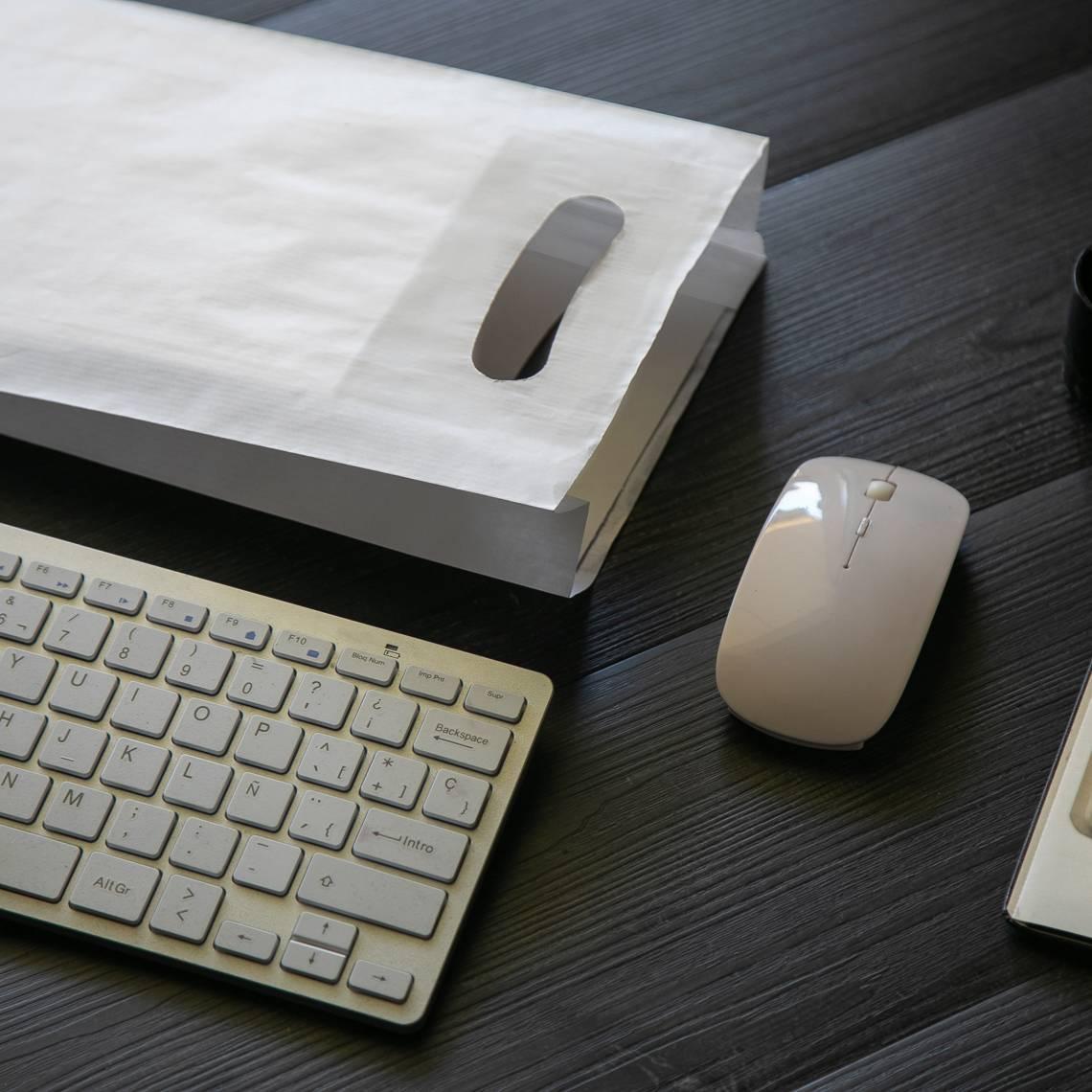 Bolsa de papel con asa troquelada que tienen al lado un ratón y teclado