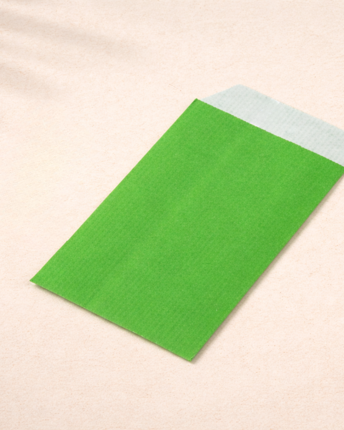 Sobres de papel pequeños verdes con lápices alrededor