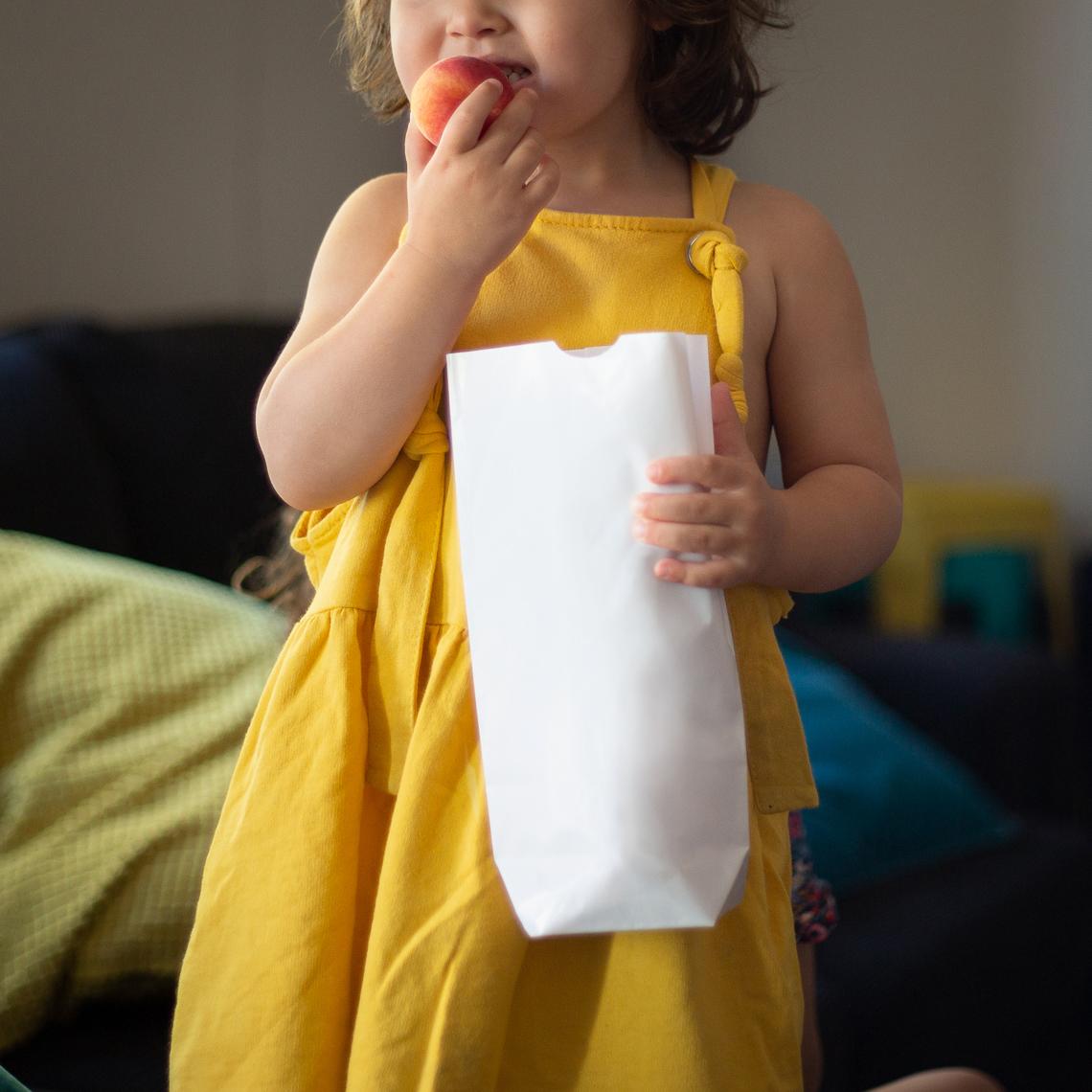 Una niña sujetando unas bolsas de papel sin asas