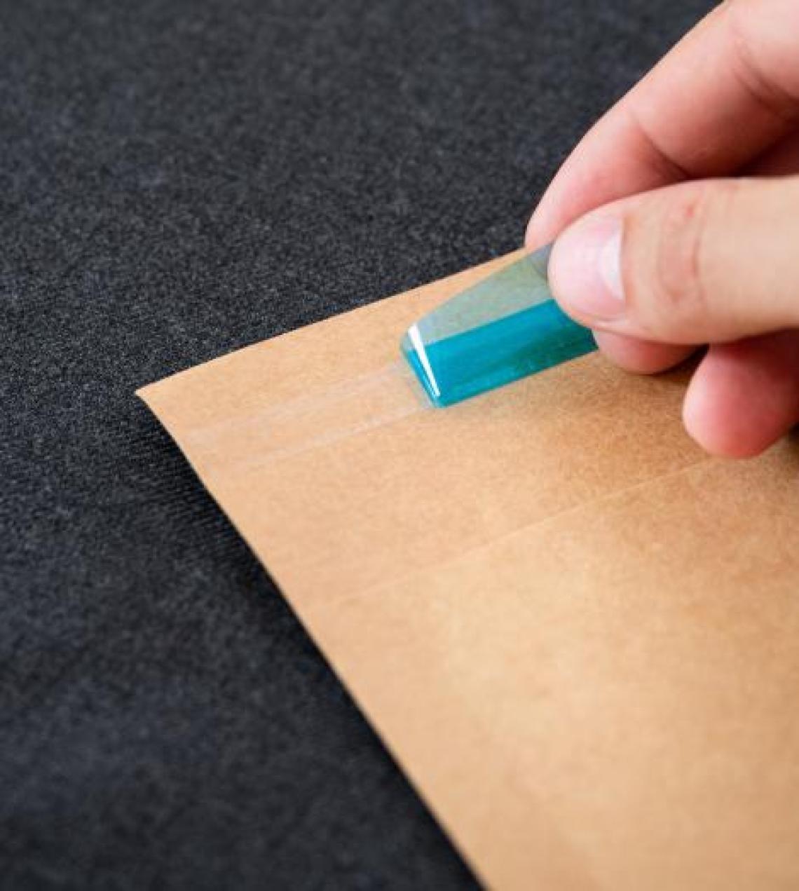 Unas manos tirando del cierre adhesivo del sobre ecommerce