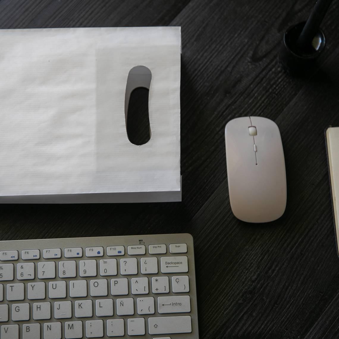 Bolsa de papel con asa troquelada que tienen al lado un ratón y teclado