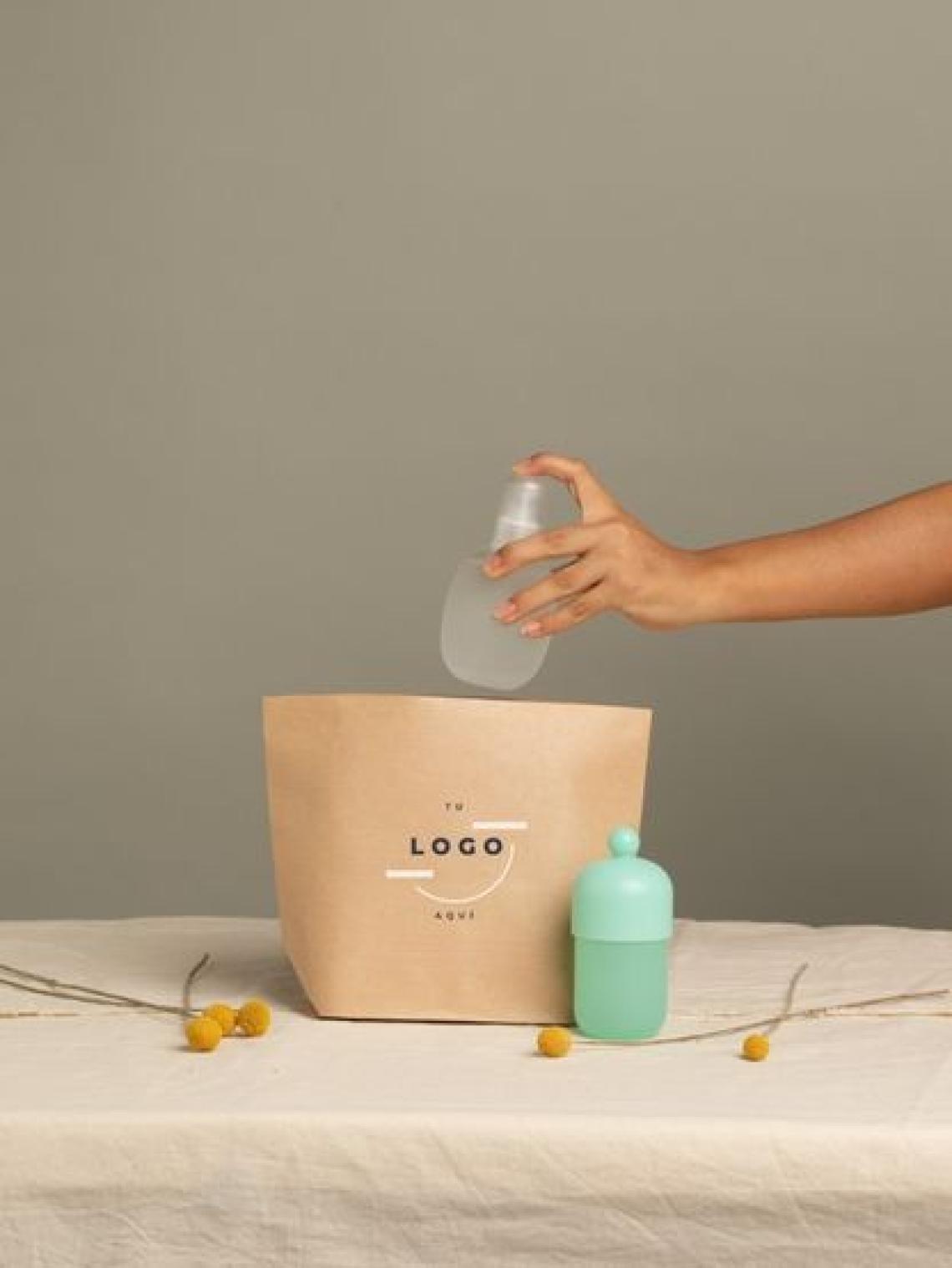 Mano colocando un frasco de cosmética en una bolsa de papel kraft hexagonal pequeña sin asas, personalizable con logotipo y fabricada en España