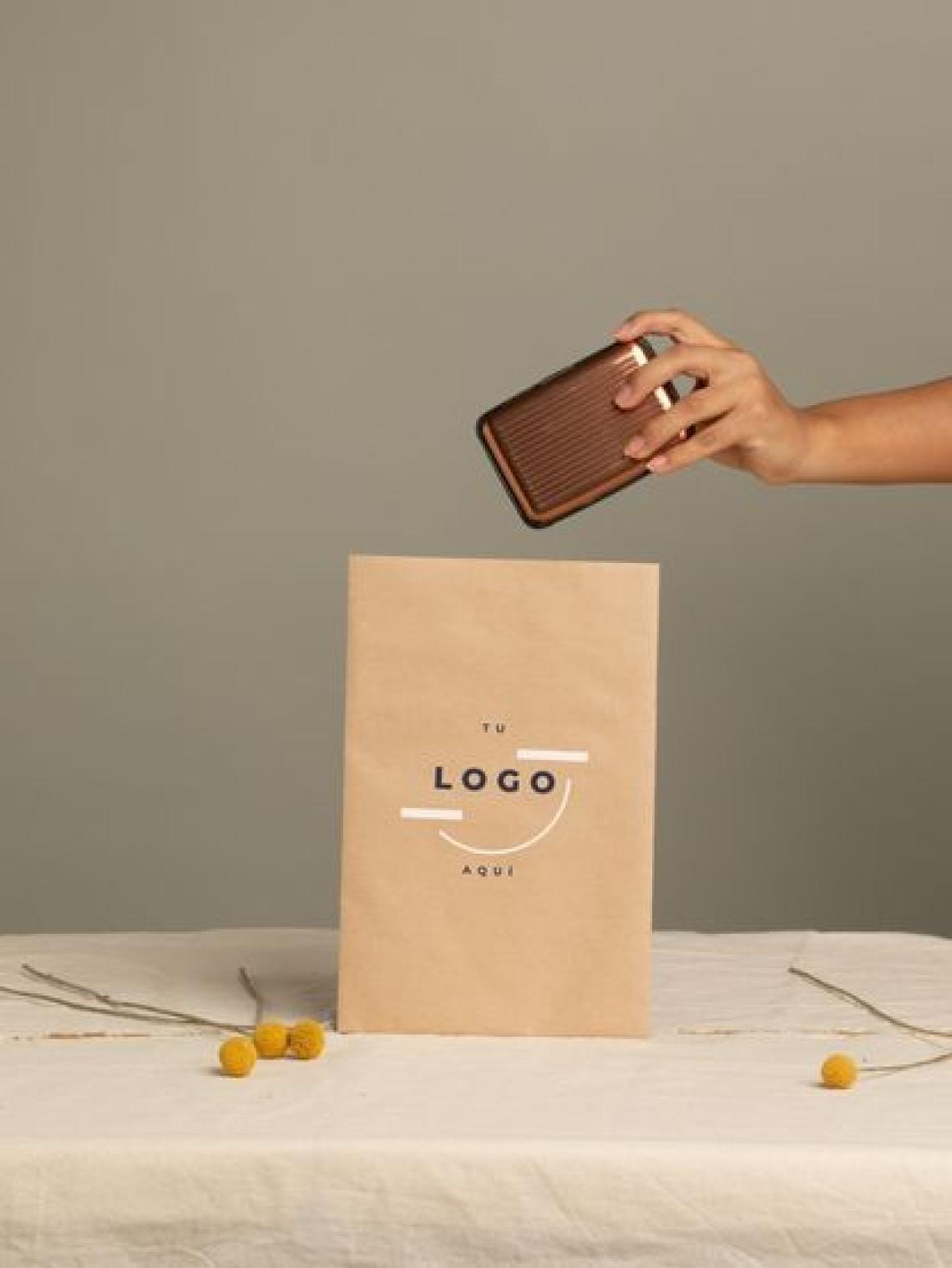Persona introduciendo un objeto en un sobre de papel kraft personalizable con logotipo