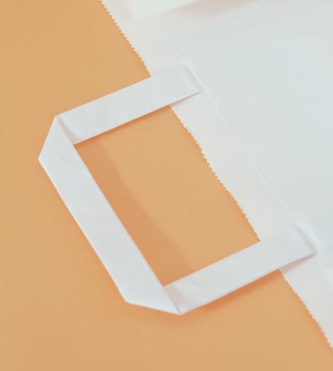 Bolsas de papel de asas planas junto a unas chaquetas