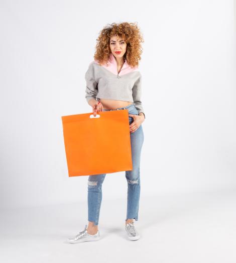 Bolsas con asas troqueladas grandes sujetadas por una mujer